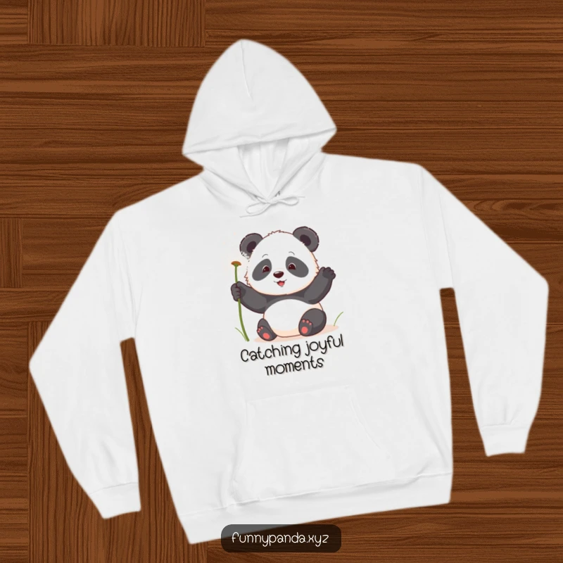 Funny kawaii panda playfully swatting fluffy dandelion seeds, featured on a cozy, warm hoodie.